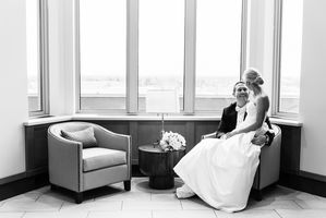 The bride and groom sit near a large window.