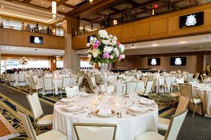 Dahnke Ballroom decorated for a wedding. Tables with white tablecloths, elaborate place settings, and pastel colored flowers fill the room.